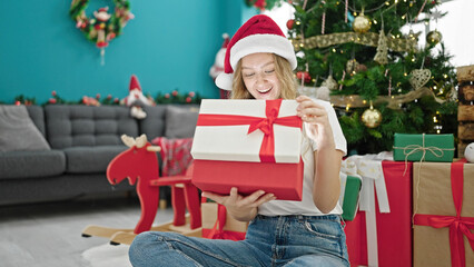 Obraz na płótnie Canvas Young blonde woman unpacking gift celebrating christmas at home