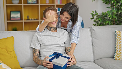 Beautiful couple smiling confident surprise with gift at home