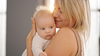 Mother and daughter hugging each other standing at home