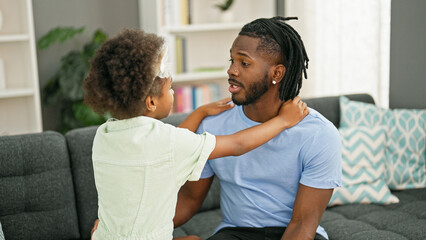 Obraz premium African american father and daughter smiling confident sitting on sofa together speaking at home