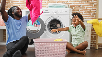 African american father and daughter smiling confident holding basket with clothes at laundry room