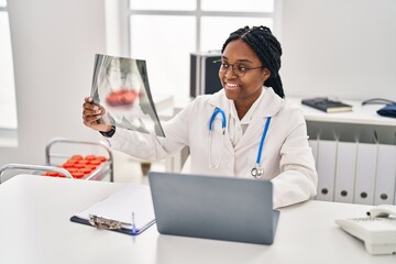 African american woman doctor looking xray sitting on table at clinic