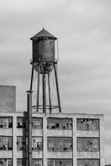 Abandoned automotive factory with broken windows and a water tower. Abandoned factories are dangerous and eyesores.