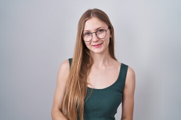 Young caucasian woman standing over white background with hands together and crossed fingers smiling relaxed and cheerful. success and optimistic