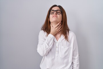 Brunette woman standing over white isolated background touching painful neck, sore throat for flu, clod and infection