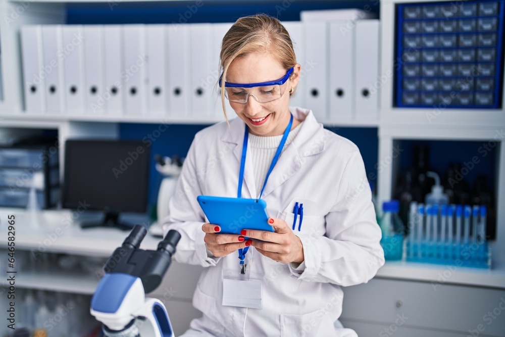 Sticker young blonde woman scientist smiling confident using touchpad at laboratory