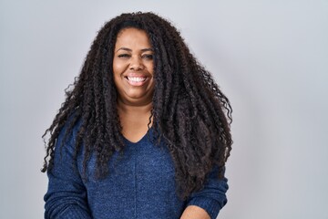 Plus size hispanic woman standing over white background with a happy and cool smile on face. lucky...