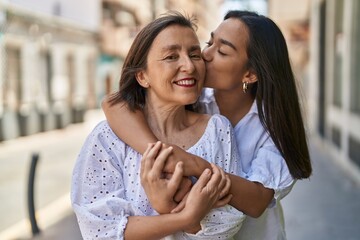 Two women mother and daughter hugging each other kissing at street