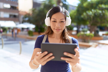 Fototapeta premium Young asian woman smiling confident watching video on touchpad at street