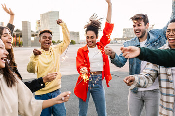 Happy young group of people having fun together on party. Millennial community of diverse friends dancing on festival celebrating together with sparkles outdoors.
