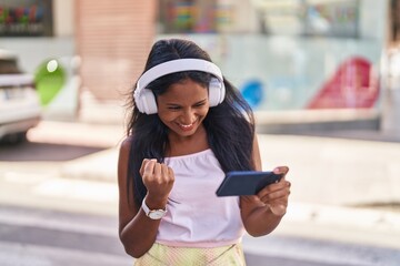 Young beautiful woman smiling confident playing video game at street