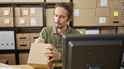 Young hispanic man ecommerce business worker writing on package at office