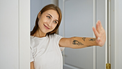 Fototapeta na wymiar Young woman leaning on door saying hello with hand smiling at home