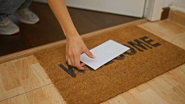 Young woman opening door holding letter at home