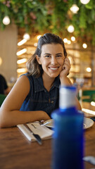 Young beautiful hispanic woman smiling happy sitting on the table at the restaurant