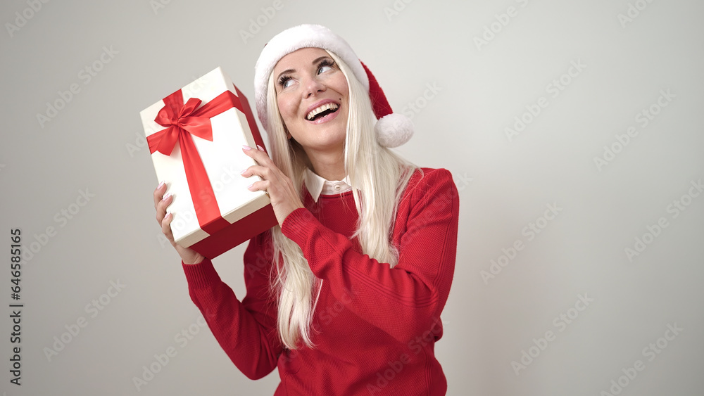 Canvas Prints Young blonde woman wearing christmas hat hearing sound gift over isolated white background