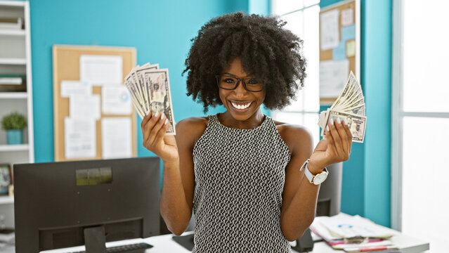 African american woman business woman holding dollars smiling at the office