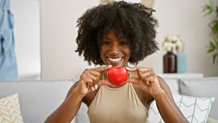 African american woman smiling confident holding heart at home