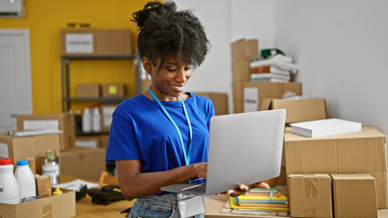African american woman volunteer using laptop smiling at charity center