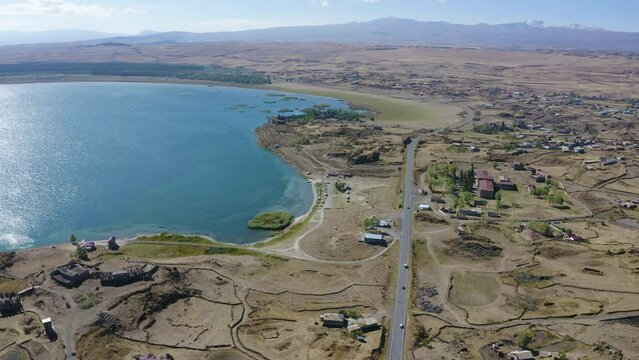 Forward reveal aerial shot of Sevan Lake, Berdkunk and Hayravank villages on sunny summer day. Gegharkunik Province, Armenia.