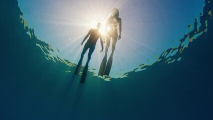 Two women swim in the sea. Underwater view of the women snorkeling on the surface at sunny calm day