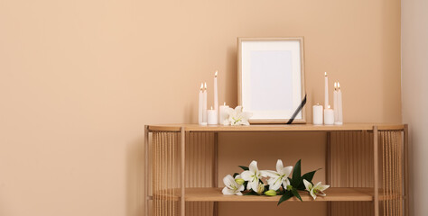 Blank photo frame, glowing candles and lily flowers on table in room. Banner for design