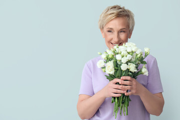 Mature woman with beautiful roses on light background