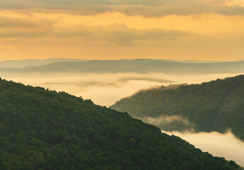 Naklejka premium Early morning sunrise view of the mist swirling over the Cheat river in the notch of the canyon by Raven Rock. Seen from Coopers Rock State Park in WV