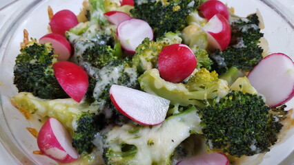 A medley of steamed broccoli, spicy radishes, and melted cheddar cheese, served with a side of crusty bread.
