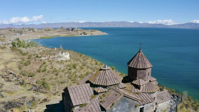 Backward reveal aerial shot of Hayravank Monastery on Sevan Lake shore on sunny summer day. Gegharkunik Province, Armenia.