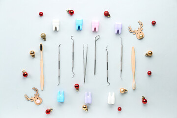 Dental tools with plastic teeth and Christmas decor on light background
