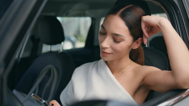 Confident lady sitting car front seat looking on smartphone with smile close up.