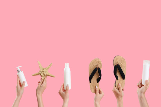 Female hands with bottles of sunscreen cream, flip flops and starfish on pink background