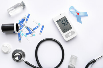 Glucometer, stethoscope, scarificators and blue ribbon on white background. Diabetes concept