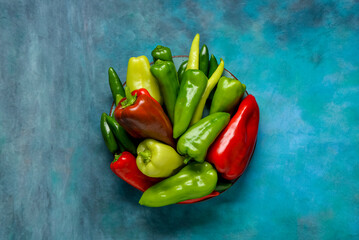 Plate with different fresh peppers on blue background