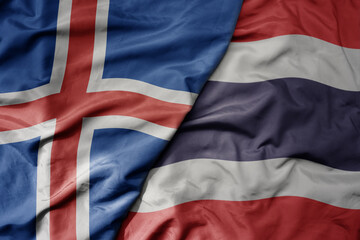 big waving national colorful flag of icelandic and national flag of thailand .