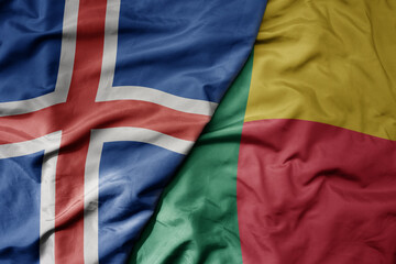 big waving national colorful flag of icelandic and national flag of benin .