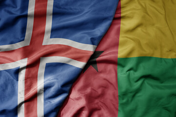 big waving national colorful flag of icelandic and national flag of guinea bissau .