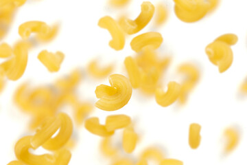 Macaroni flying explosion, yellow macaronis pasta float explode, abstract cloud fly. Curved macaroni pasta splash throwing in Air. White background Isolated freeze motion selective focus