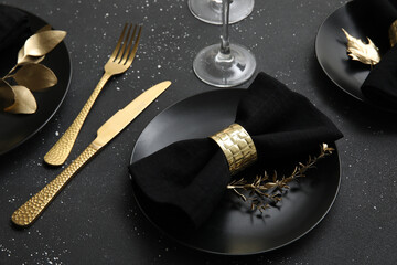 Elegant table setting with golden leaves and cutlery on black table