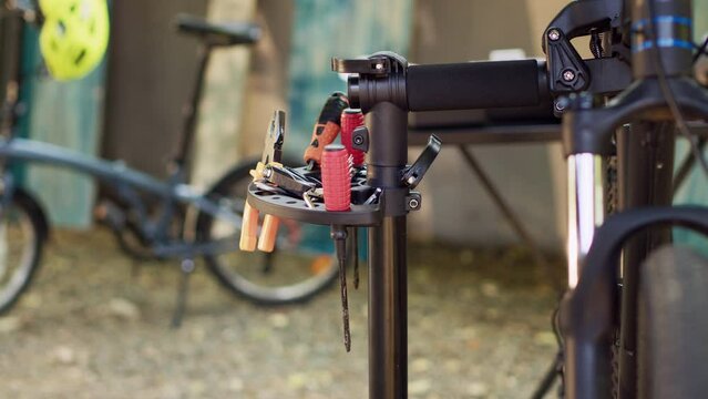 Outdoor bicycle repair and maintenance with professional tools placed on repair-stand. The lens capturing various specialized tools prepared for bike fixing and servicing in home yard.