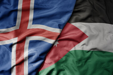 big waving national colorful flag of icelandic and national flag of jordan .