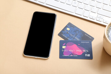 Mobile phone with credit cards and computer keyboard on beige background, closeup. Online shopping