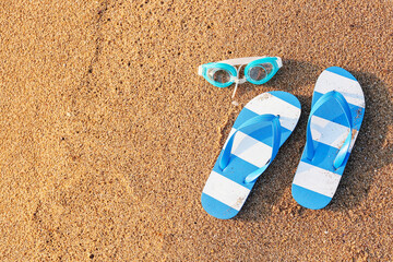 Stylish flips flops with goggles on sand at resort