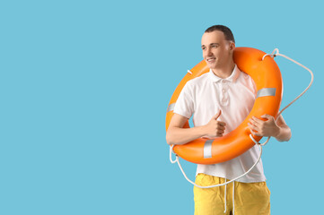 Young man with ring buoy on blue background