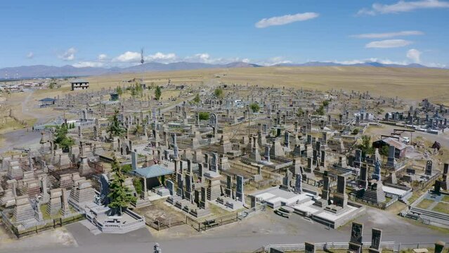 Backward reveal aerial shot of Noratus cemetery on sunny summer day. Sevan lake, Gegharkunik Province, Armenia.