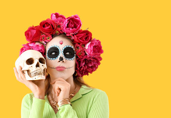 Thoughtful young woman with painted skull on yellow background. Mexico's Day of the Dead (El Dia de Muertos) celebration