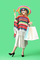 Young woman with painted skull, maracas and shopping bags on green background. Mexico's Day of the Dead (El Dia de Muertos) celebration