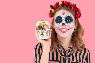 Young woman with painted skull on pink background, closeup. Mexico's Day of the Dead (El Dia de Muertos) celebration