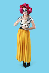 Young woman with skulls on blue background. Mexico's Day of the Dead (El Dia de Muertos) celebration